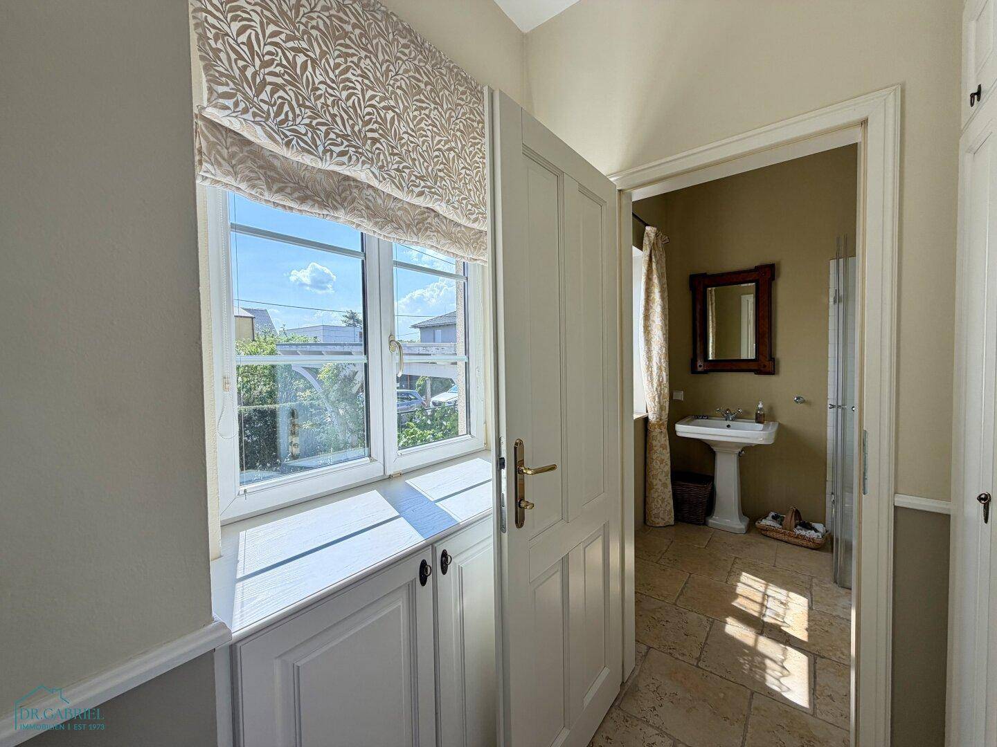 Heller Flur mit Einbauschränken und Blick in ein Badezimmer mit Fenster.