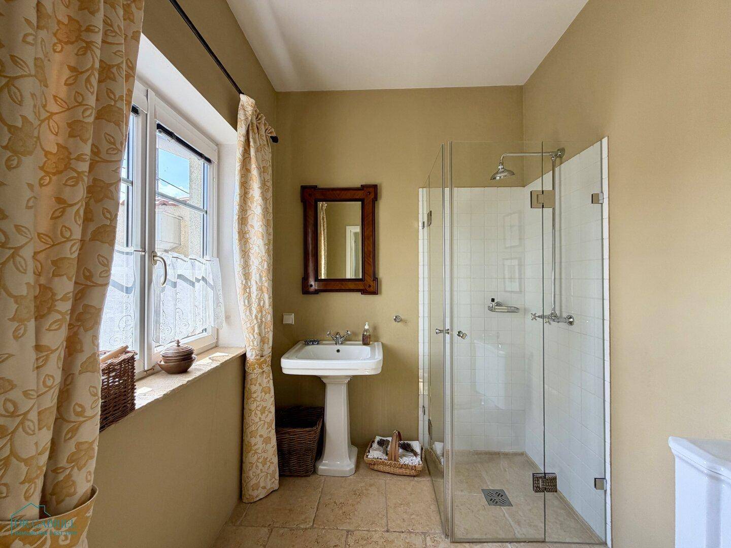 Helles Badezimmer mit Duschkabine, Waschtisch und Fenster, ausgestattet mit Fliesenboden.