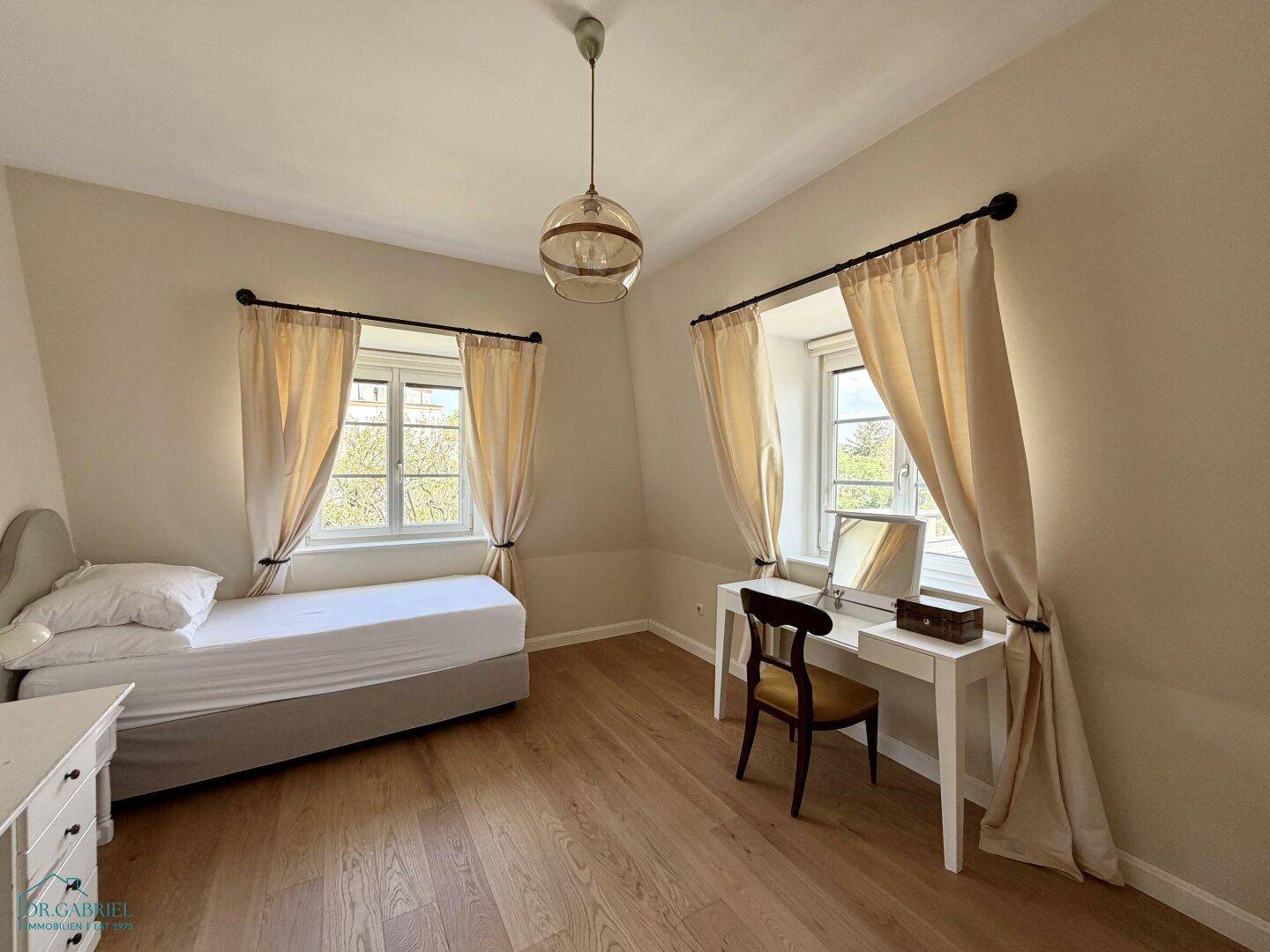 Helles Schlafzimmer mit Einzelbett, Schreibtisch und Holzboden, ideal als Kinder- oder Gästezimmer.