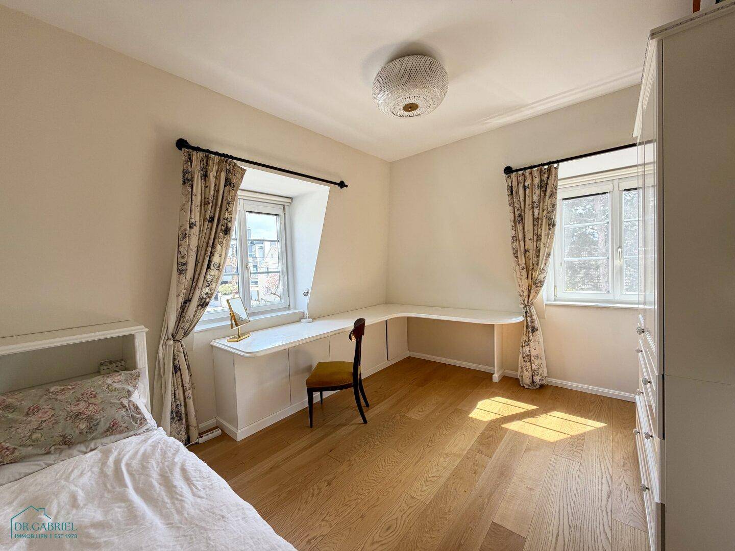 Freundliches Schlafzimmer mit großem Schreibtisch, Holzboden und Einbauschrank, ideal zum Arbeiten.