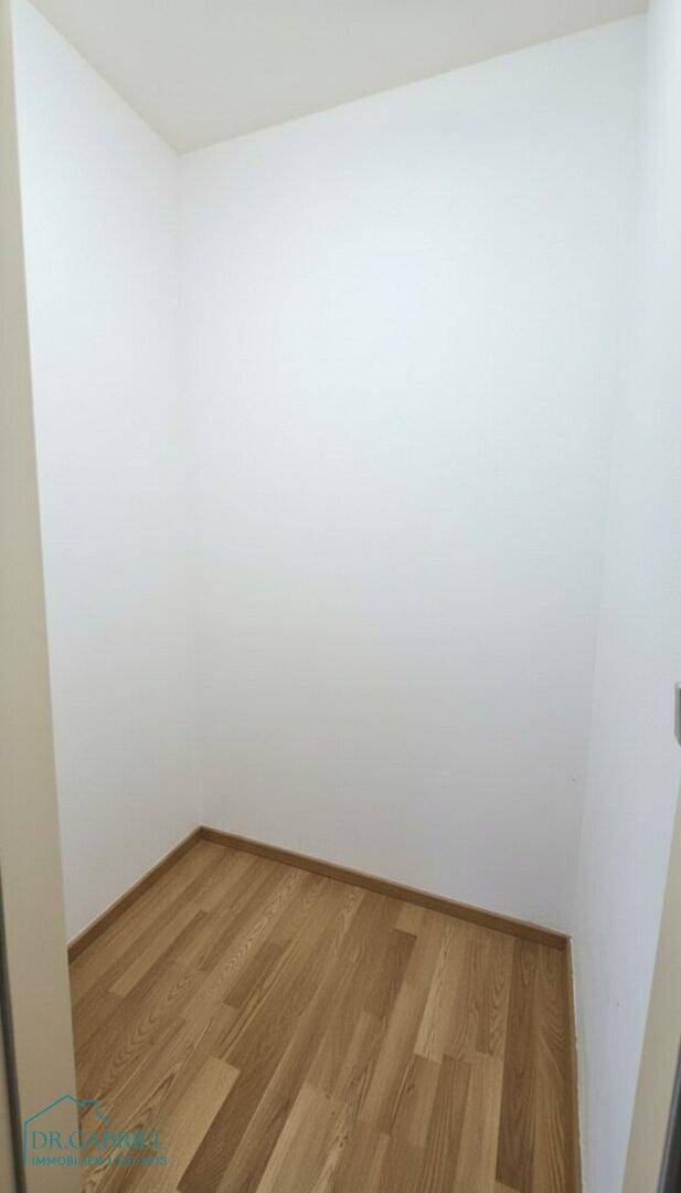 Kleiner, leerer Abstellraum oder begehbarer Kleiderschrank mit hellem Parkettboden.