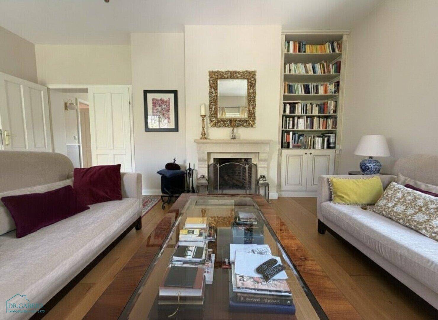 Elegantes Wohnzimmer mit Kamin, Einbauregal und bequemen Sofas, ideal zum Entspannen.