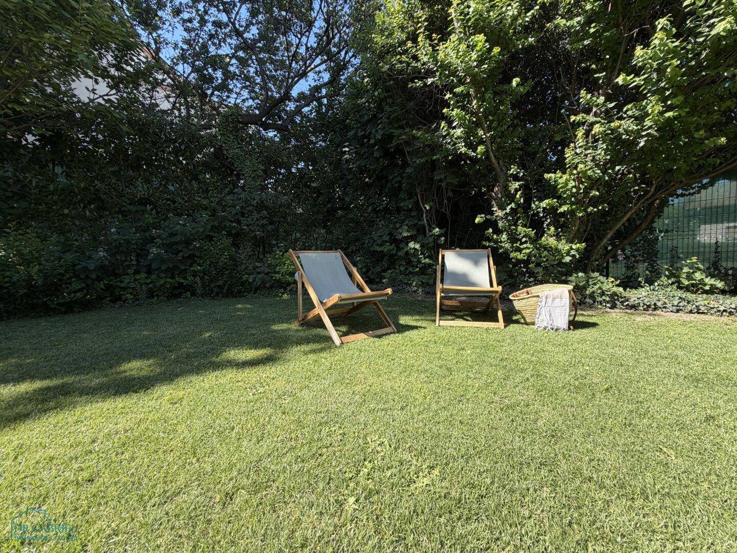 Ruhiger Gartenbereich mit Liegestühlen auf dem Rasen, ideal zum Entspannen im Grünen unter Bäumen.