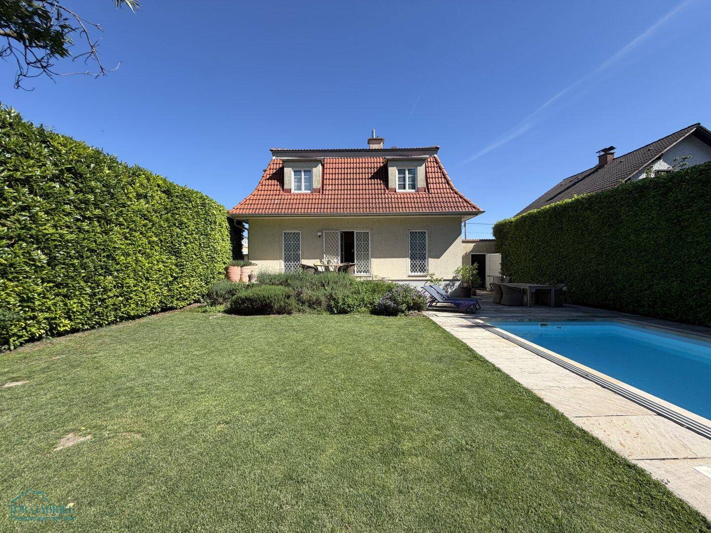 Weitläufiger Garten mit großem Rasen, privatem Pool und dem charmanten Haus im Hintergrund.