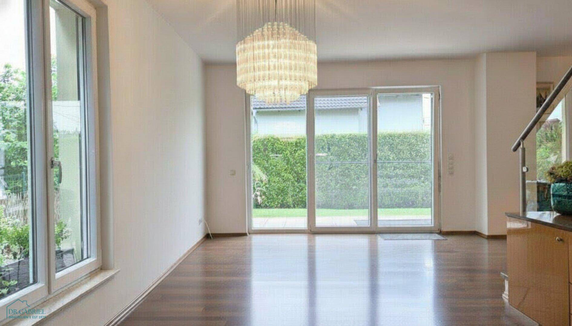 Heller Raum mit Holzboden, großen Fenstern und Blick ins Grüne, ideal für Wohn- oder Essbereich.