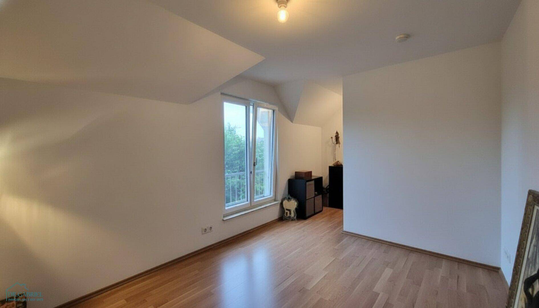 Helles Schlafzimmer im Dachgeschoss mit Holzboden, schrägen Wänden und französischem Balkon.