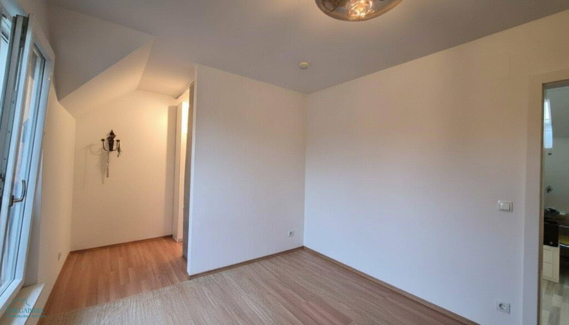 Dachgeschosszimmer mit Holzboden und schrägen Wänden, ideal als Schlaf- oder Arbeitszimmer.