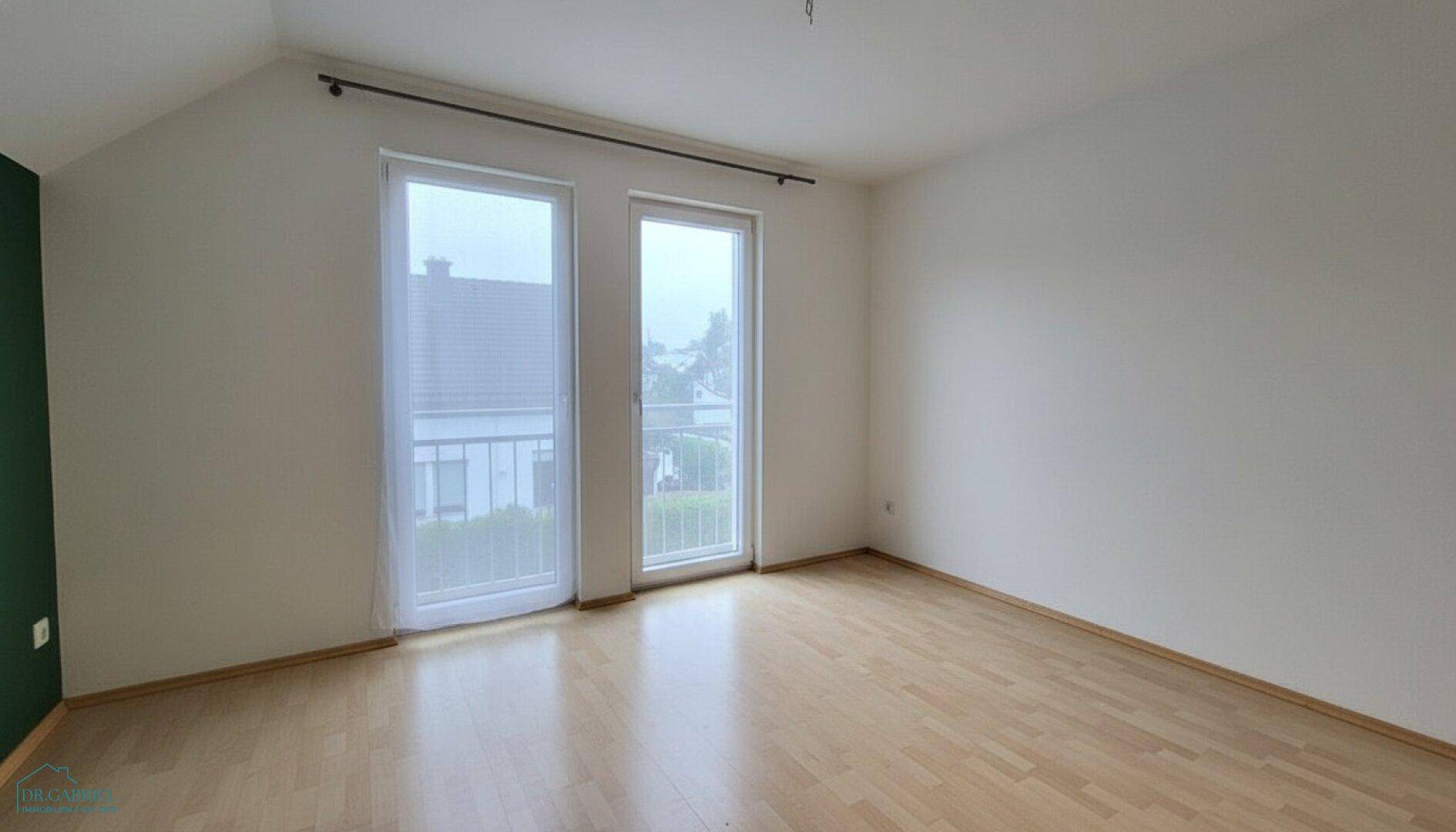 Geräumiges Dachgeschosszimmer mit Holzboden und französischem Balkon, hell und freundlich.