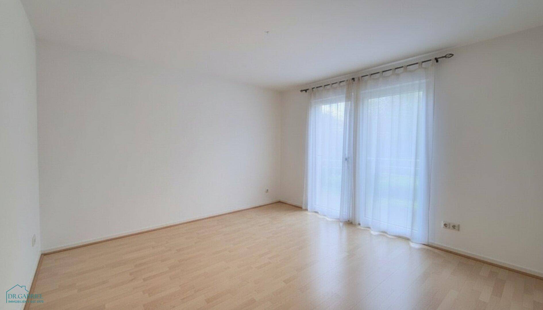Helles Zimmer mit Holzboden und großen Fenstern, vielseitig nutzbar.