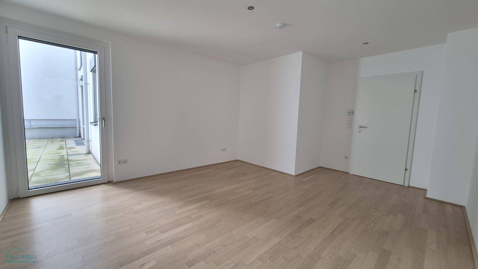 Heller Raum mit Parkettboden und Zugang zu einem Außenbereich, vielseitig nutzbar.