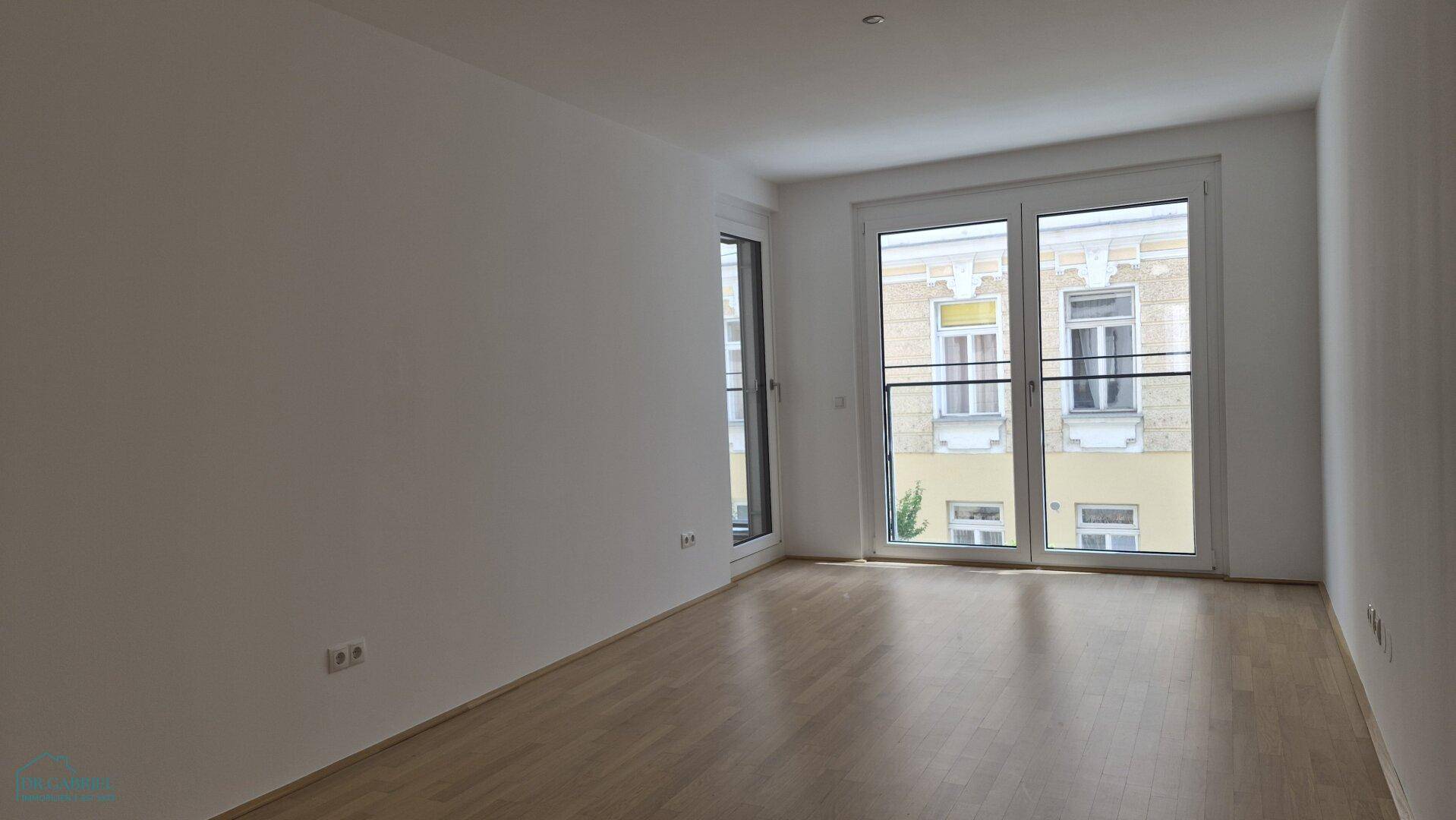 Geräumiges, leeres Zimmer mit hellem Parkettboden und großen Fenstern, vielseitig nutzbar.