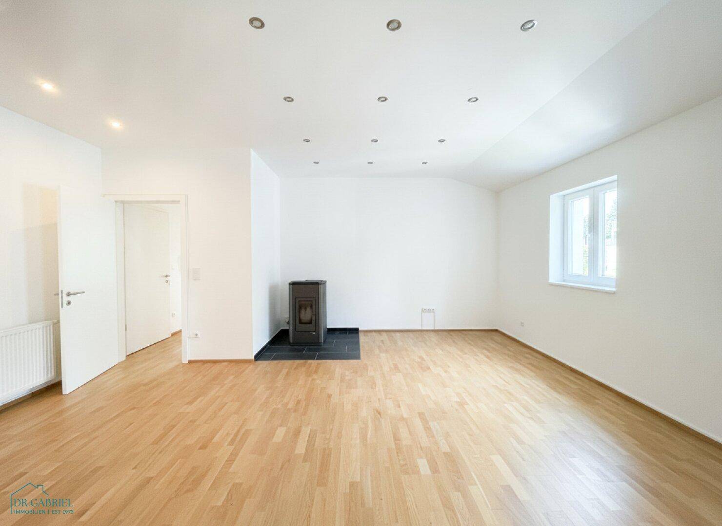 Dachgeschossraum mit Parkettboden, Einbaustrahlern und einem modernen Kaminofen.