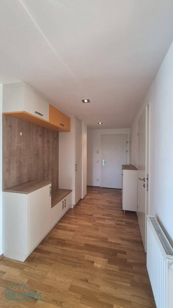 Heller Flur mit Holzboden, Einbauschränken und Garderobe.