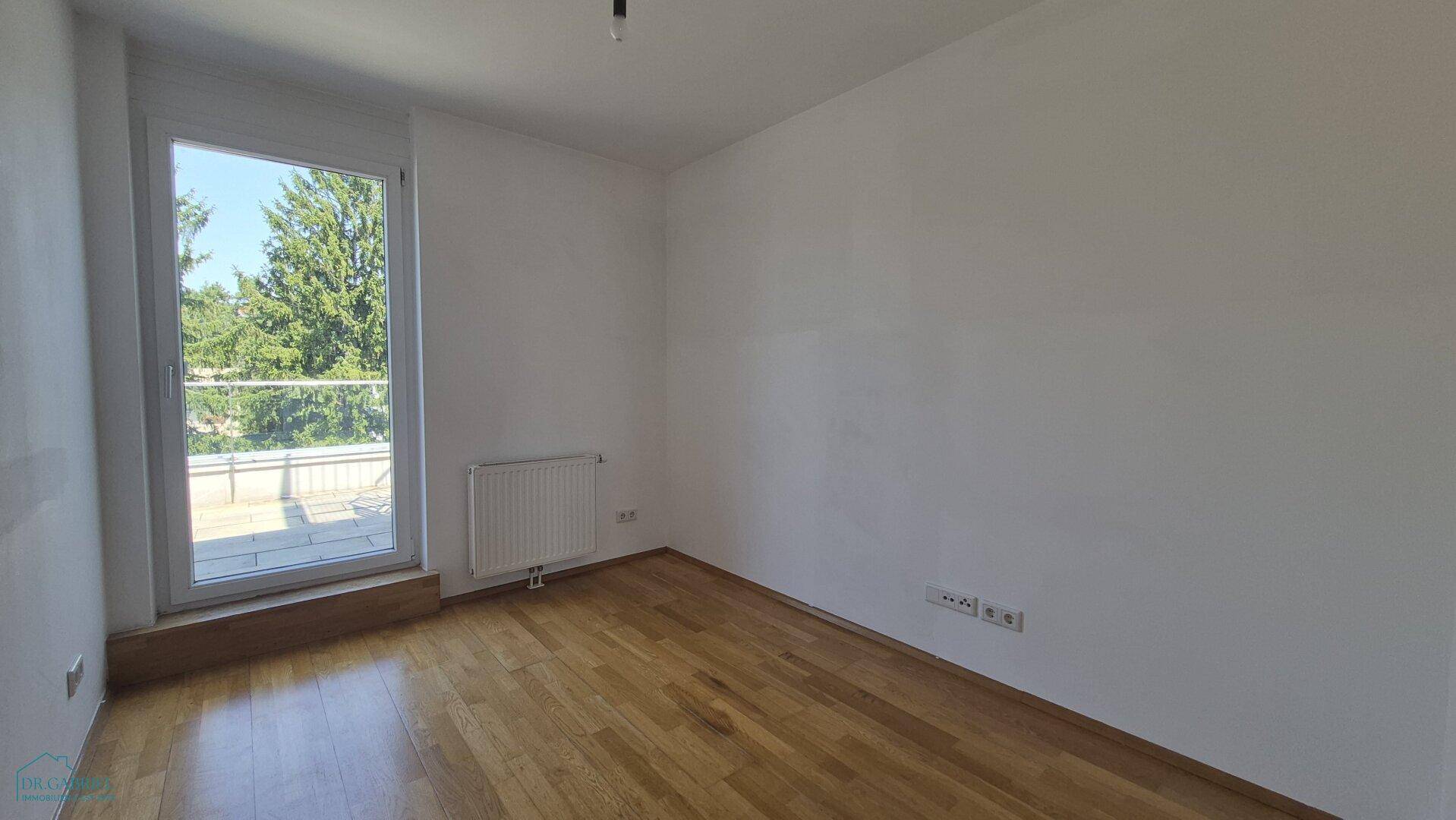 Helles Schlafzimmer mit Holzboden, Fenster und Heizkörper.