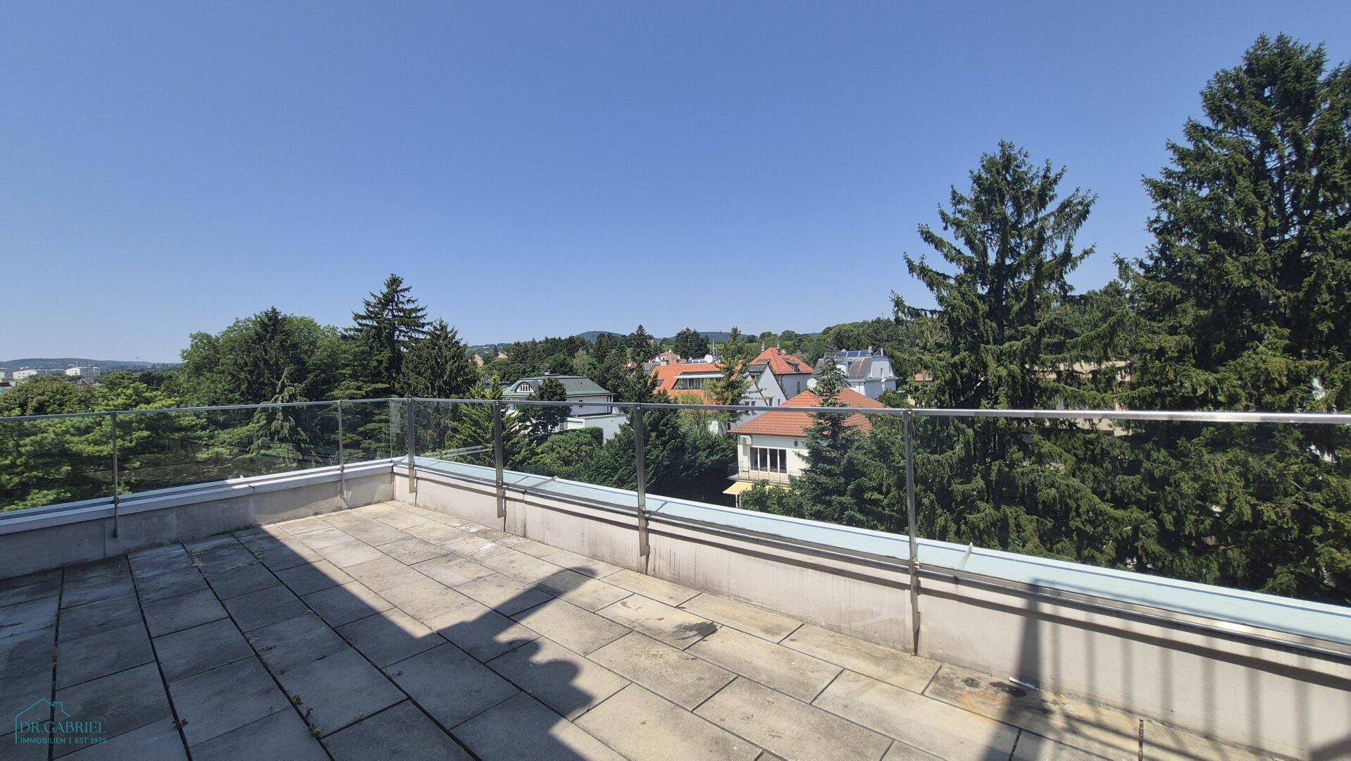 Große Terrasse mit Glasgeländer und weitem Blick ins Grüne und auf die Umgebung.
