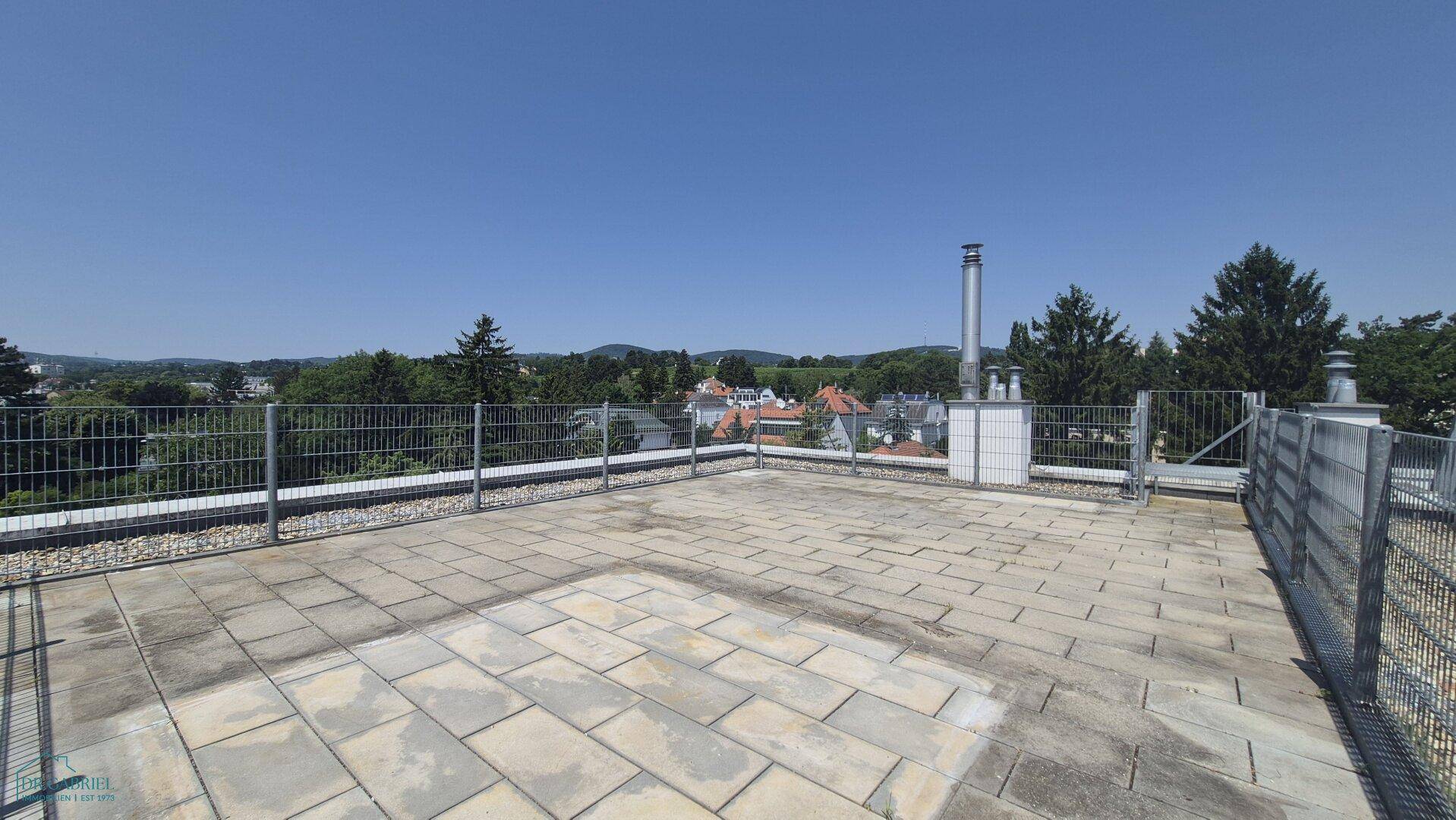 Geräumige Dachterrasse mit Steinplatten und weitem Blick ins Grüne und auf die Umgebung.