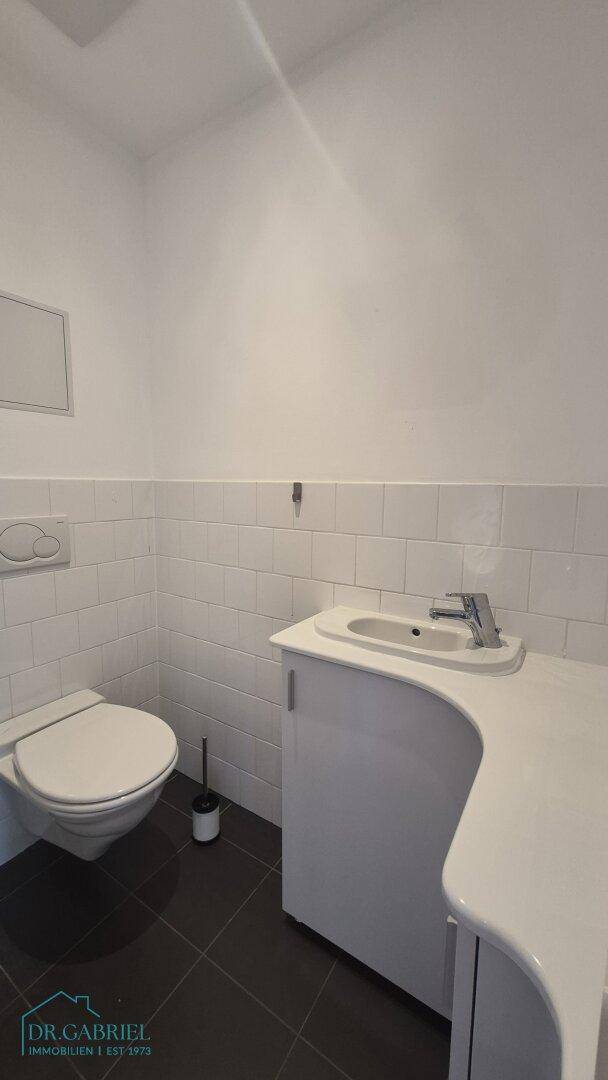 Helles Gäste-WC mit modernem Waschbecken und Wand-WC.