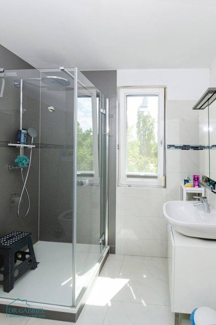 Modernes Badezimmer mit begehbarer Dusche, Einzelwaschbecken und Fenster für Tageslicht.