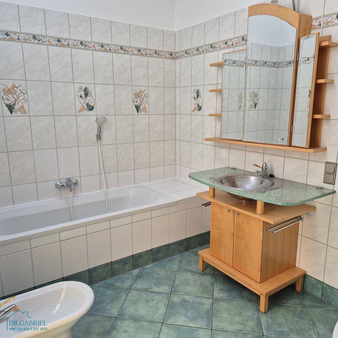 Badezimmer mit Badewanne, Waschbecken, Bidet und dekorativen Fliesen, die einen traditionellen Stil aufweisen.