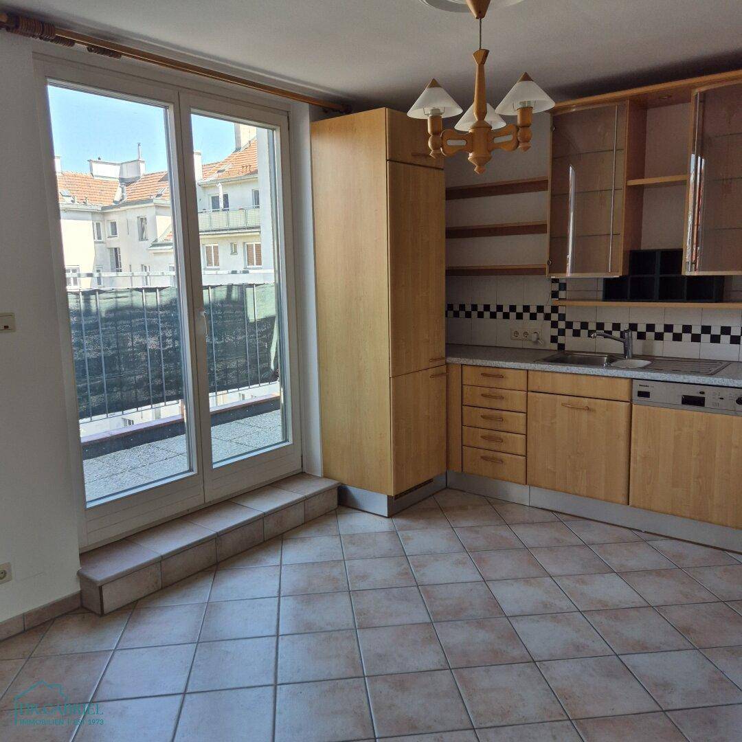 Helle Küche mit Holzmöbeln und großen Fenstertüren, die zu einem Balkon führen.