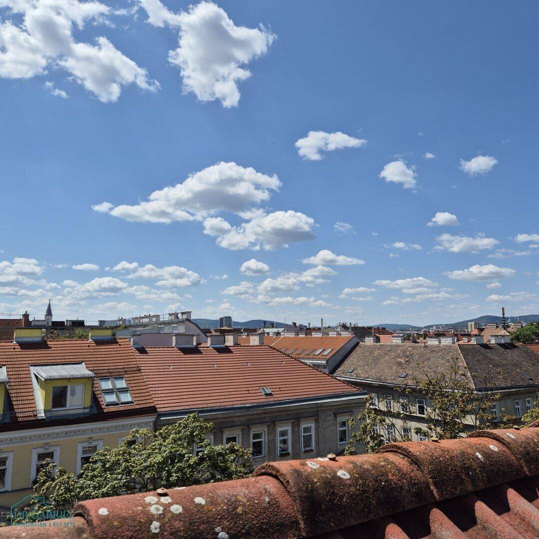 Weitläufiger Blick über die Dächer der Stadt unter einem strahlend blauen Himmel mit vielen Wolken.