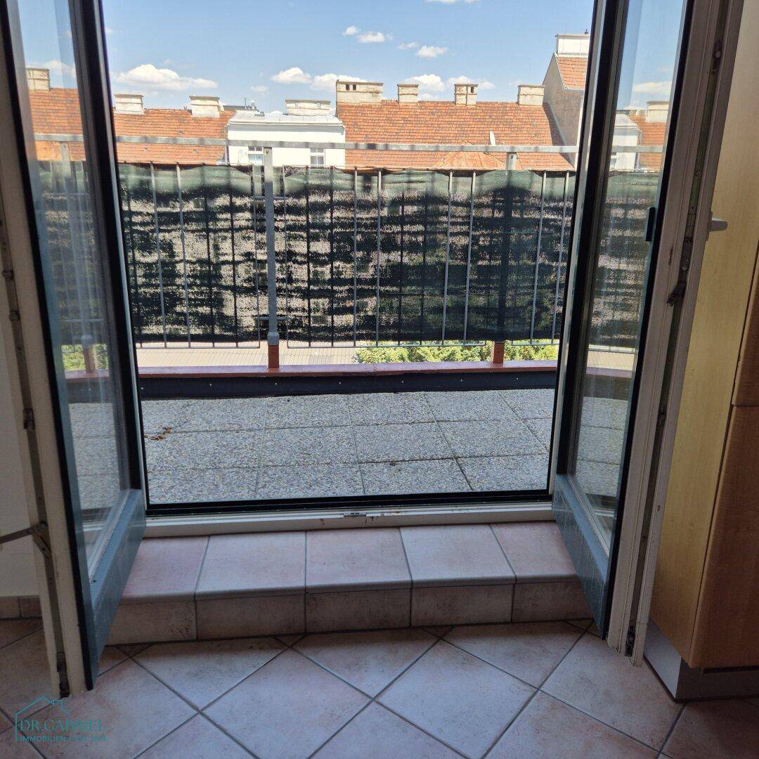 Blick aus der Küche auf den Balkon durch die geöffneten Türen, der eine Erweiterung des Wohnraums bietet.