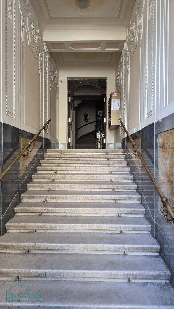 Repräsentatives Treppenhaus mit Steinstufen, verzierten Wänden und eleganten Handläufen.
