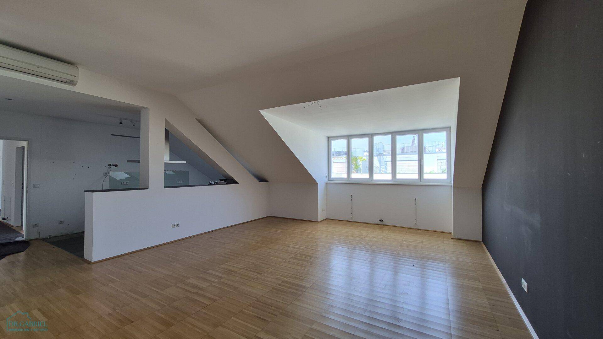 Geräumiger, heller Wohnbereich mit Parkettboden, großen Fenstern und Dachschrägen.