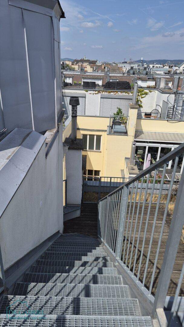 Metalltreppe führt von der Dachterrasse hinunter mit Blick auf die umliegenden Gebäude.