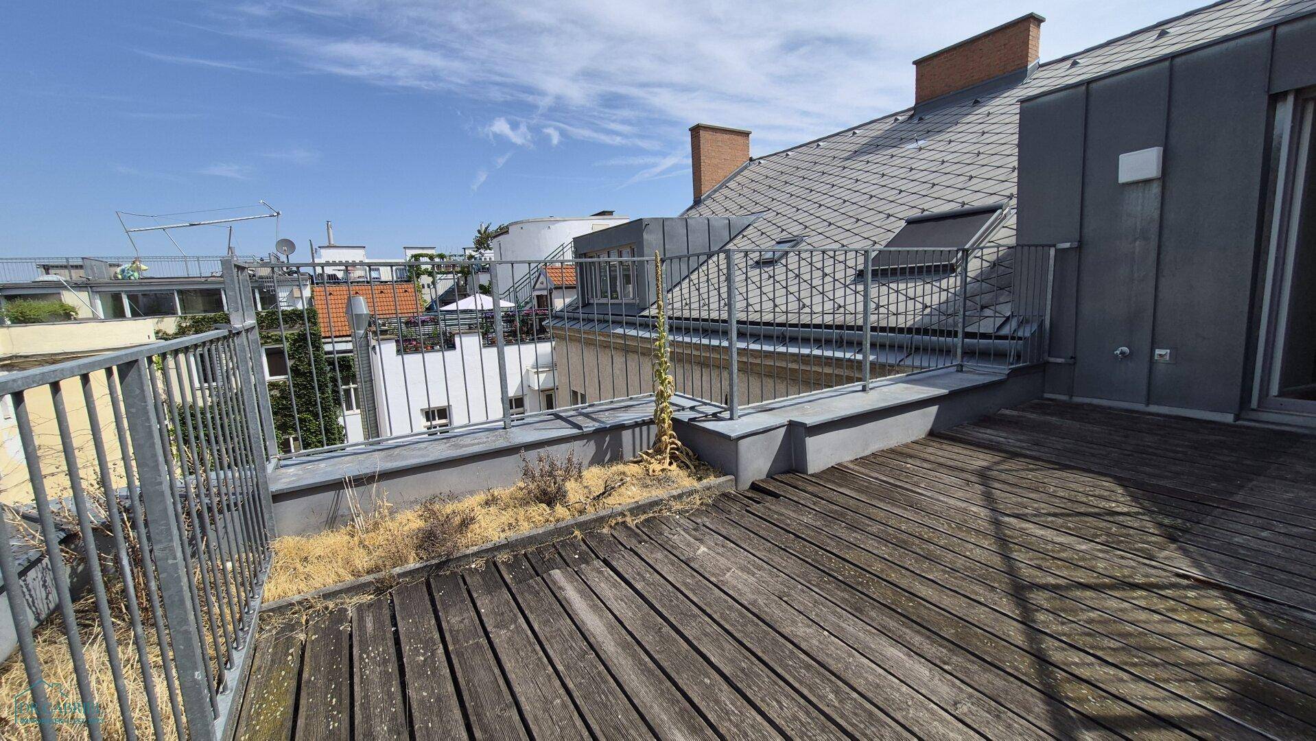 Leere Dachterrasse mit Holzbelag und Metallgeländer, bereit für individuelle Gestaltung.