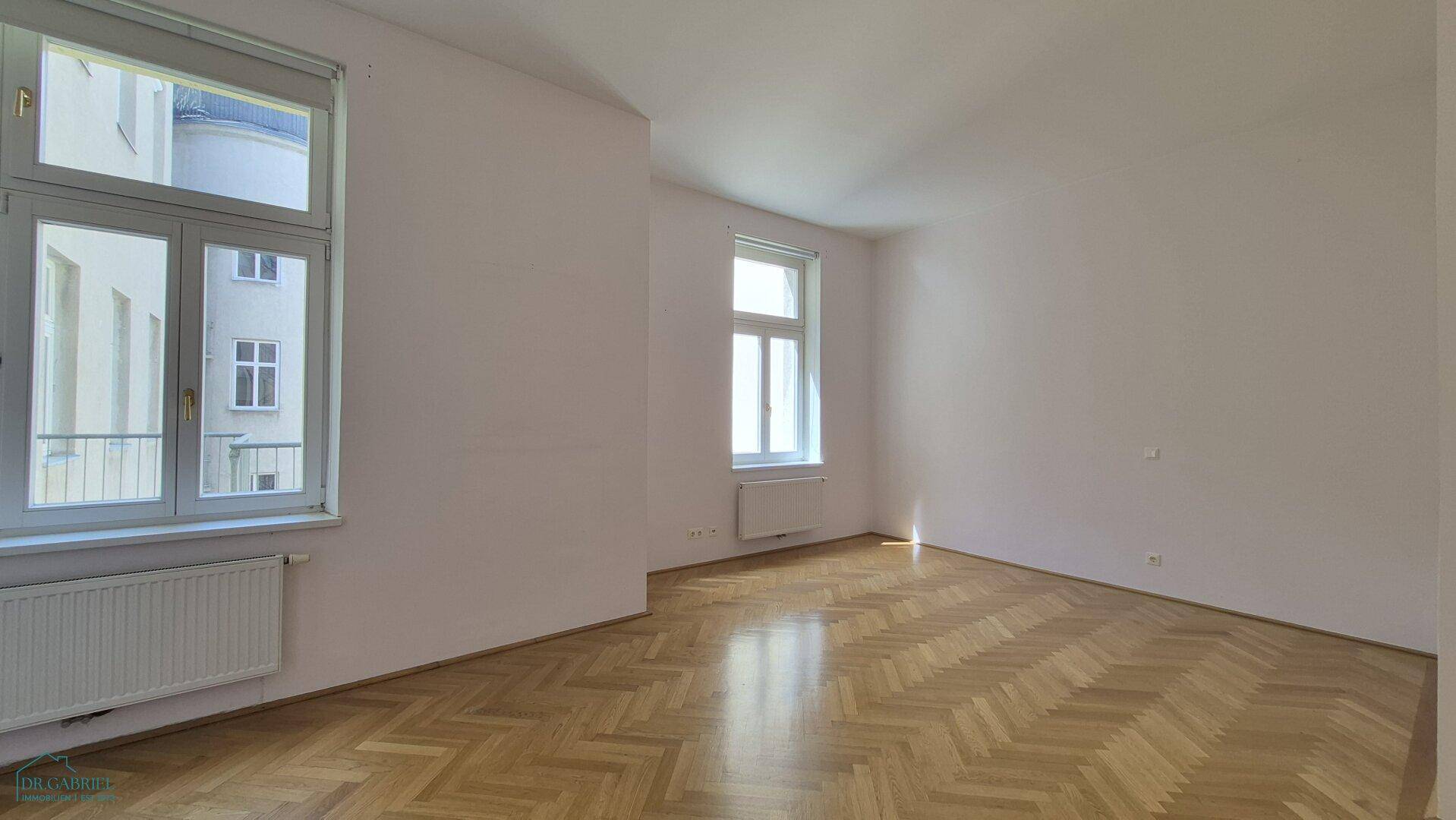 Helles Zimmer mit Fischgrätparkett und Blick auf den Innenhof, vielseitig nutzbar.