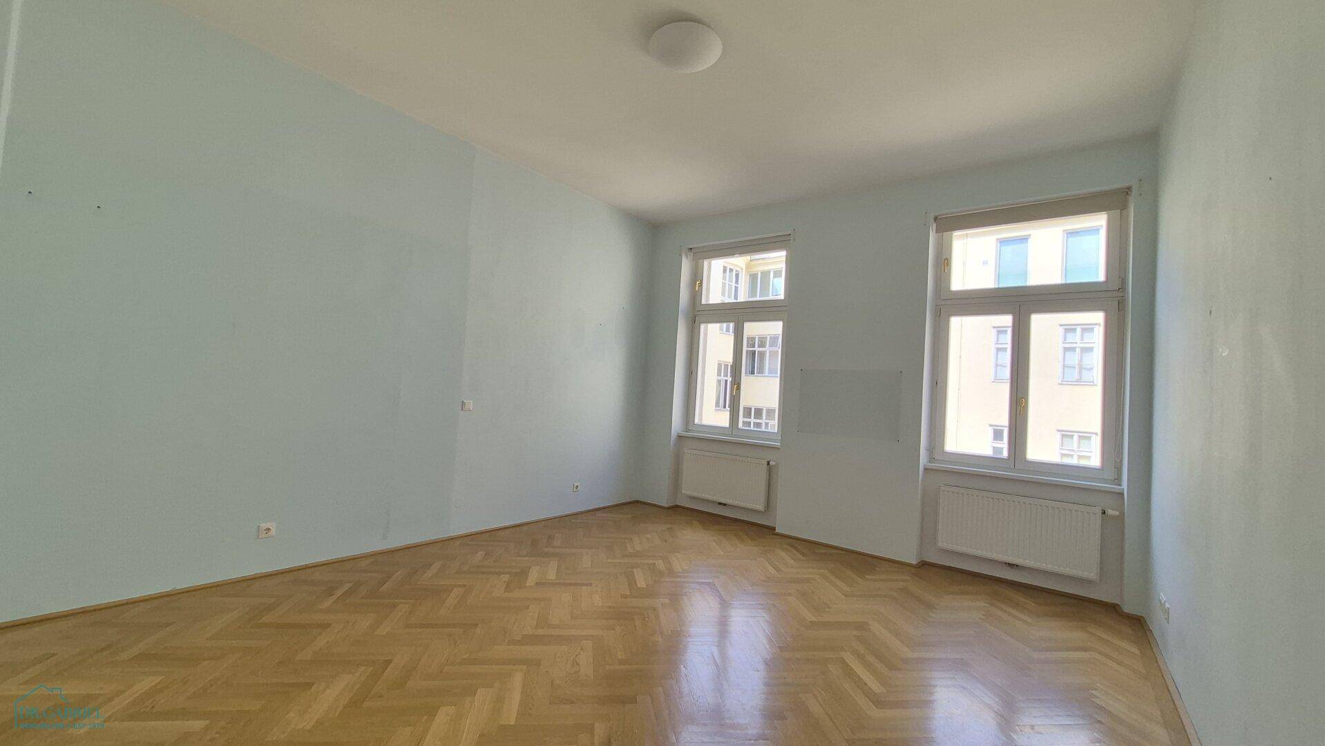 Ruhiges Zimmer mit hellblauen Wänden und Fischgrätparkett, bietet eine entspannte Atmosphäre.