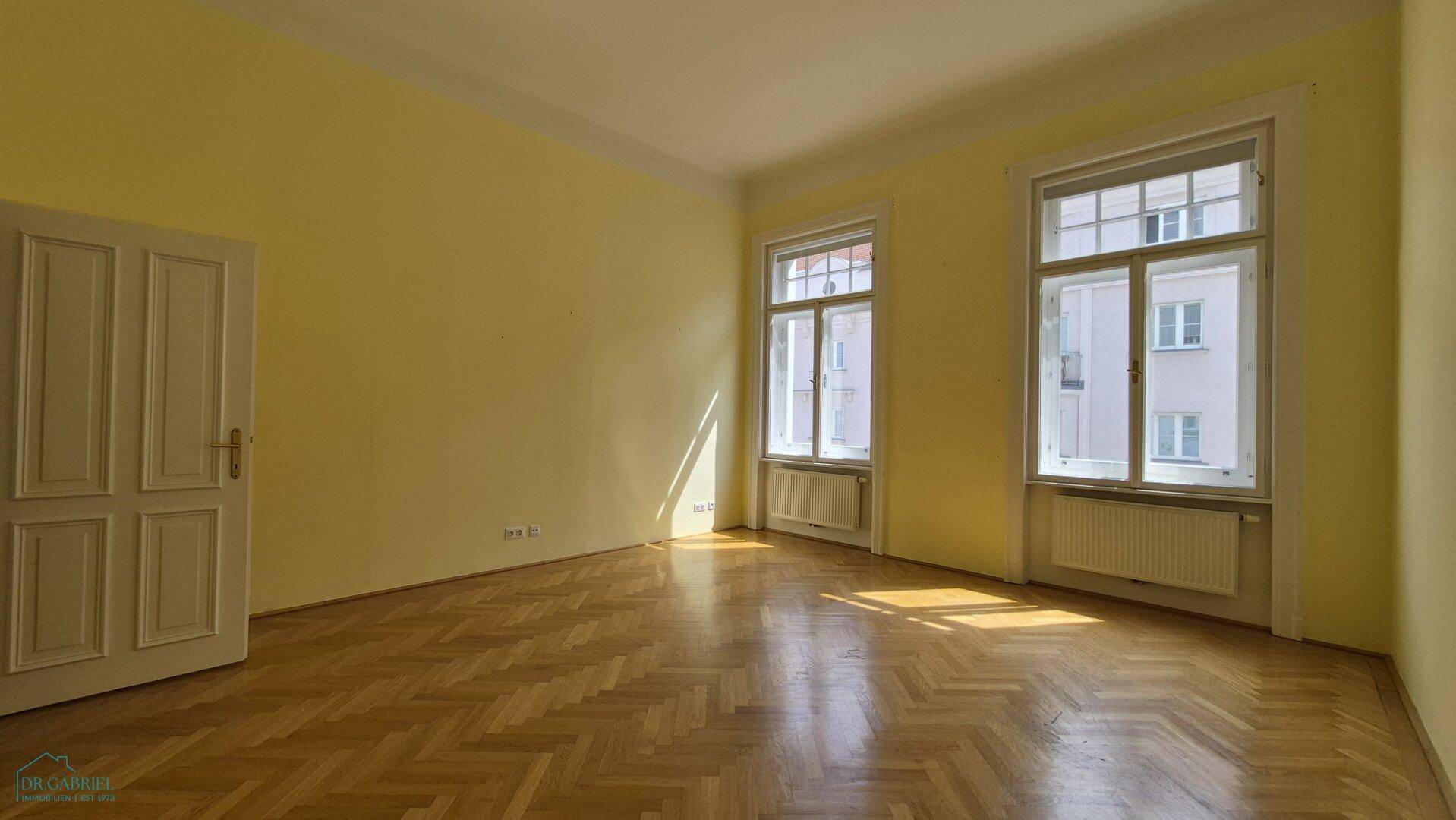 Sonniger Raum mit gelben Wänden und Fischgrätparkett, ideal für ein helles Ambiente.