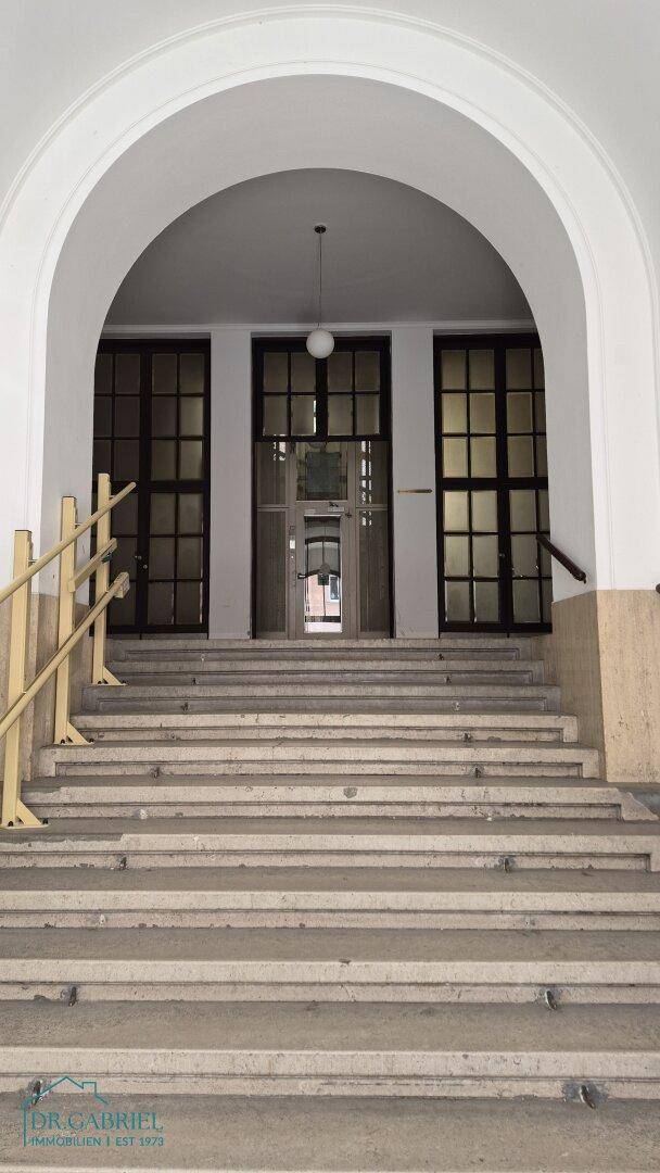 Repräsentativer Eingangsbereich mit breiter Treppe und hohen Türen in einem Altbau.