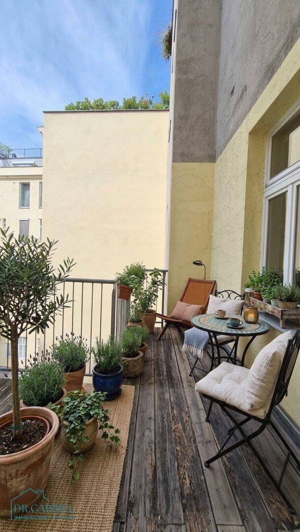 Gemütlicher Balkon mit Holzboden, Pflanzen und Sitzgelegenheiten für entspannte Stunden im Freien.