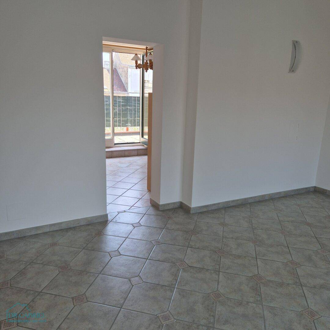 Heller Innenraum mit Fliesenboden und Zugang zu einem Balkon oder einer Terrasse.