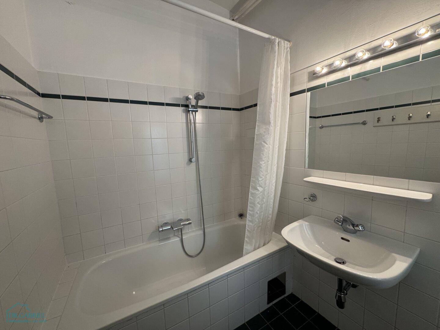 Badezimmer mit Badewanne, Duschvorhang, Waschbecken und weißen Fliesen.