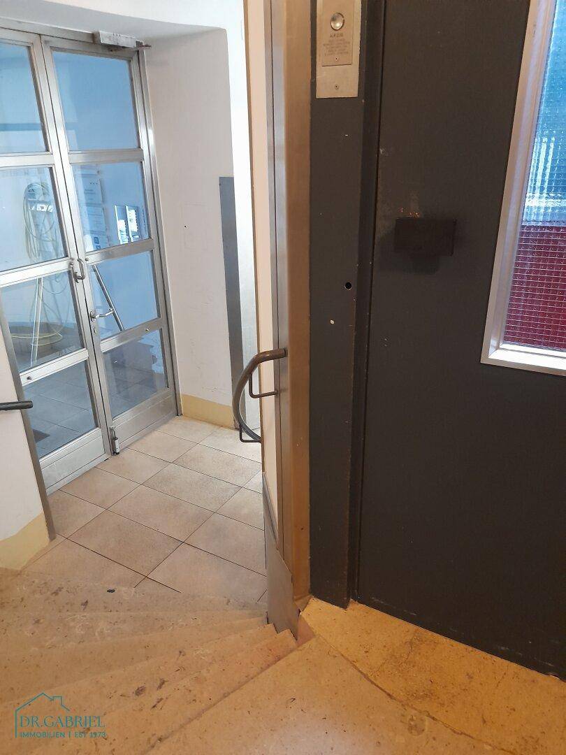 Eingangsbereich mit Steintreppe und Zugang zum Aufzug in einem Altbau.