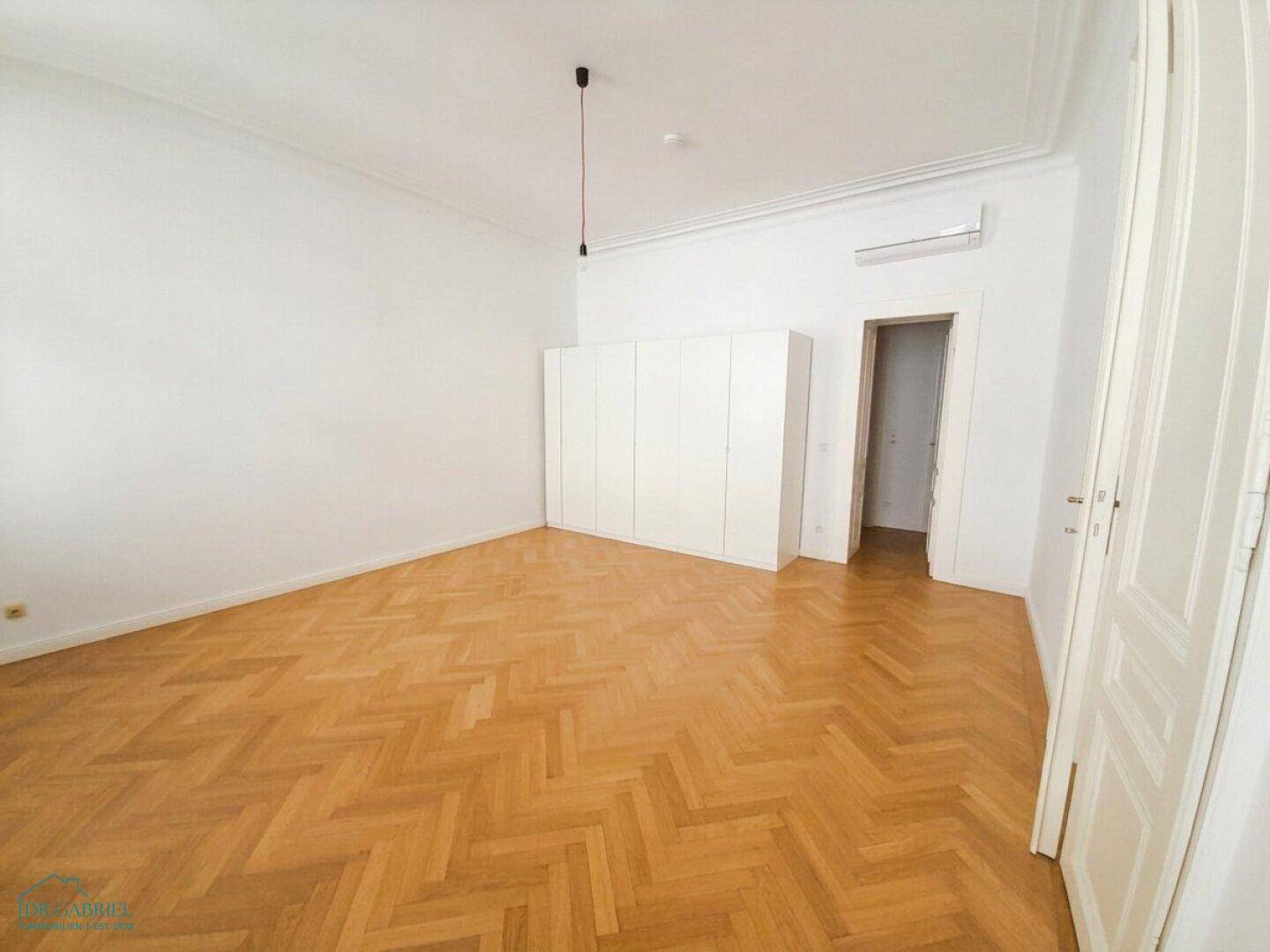 Helles Schlafzimmer mit Einbauschrank, Fischgrätparkett und Klimaanlage.