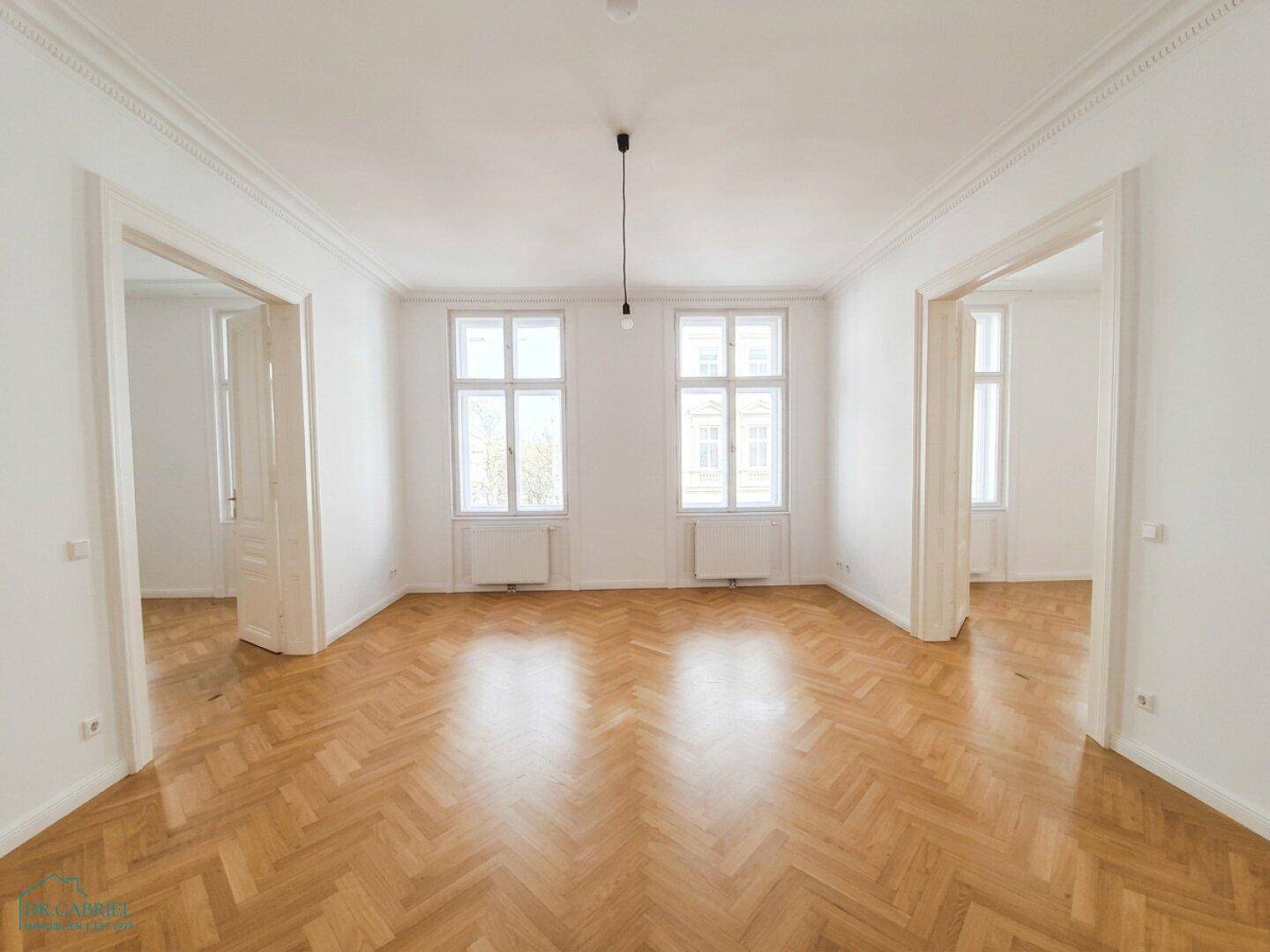 Helles, leeres Zimmer mit Fischgrätparkett und hohen Decken, bereit zur individuellen Gestaltung.