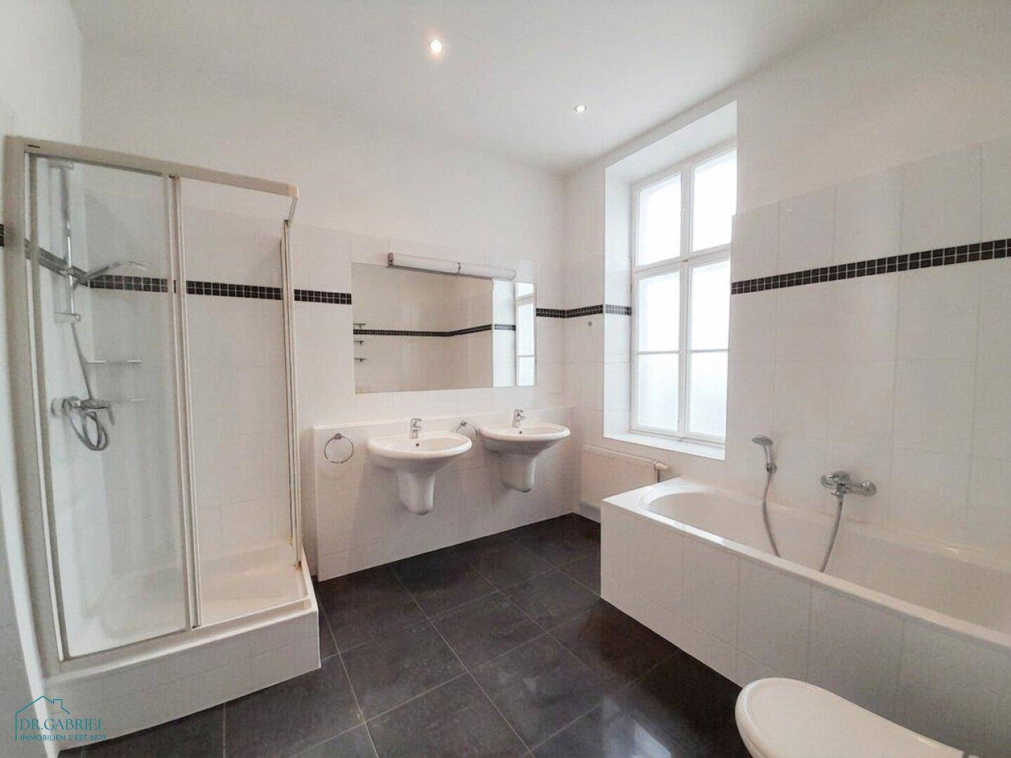 Geräumiges Badezimmer mit zwei Waschbecken, Badewanne und separater Dusche.
