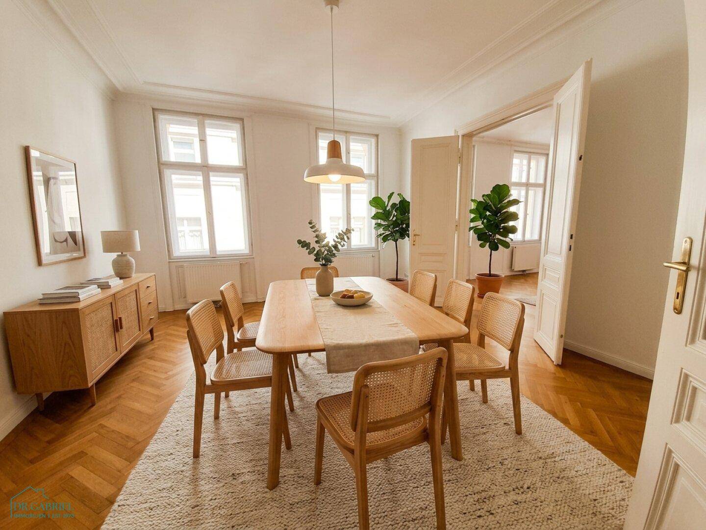 Heller Essbereich mit Holztisch, Rattan-Stühlen und Fischgrätparkettboden.