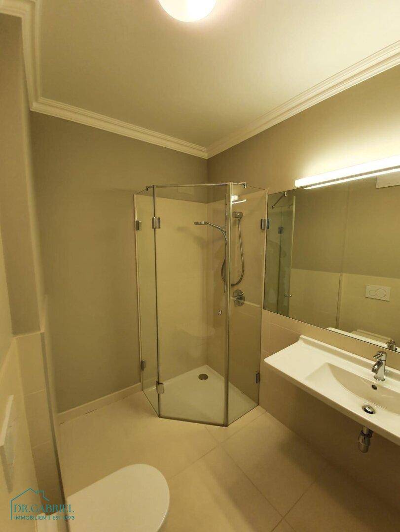 Modernes Badezimmer mit Duschkabine, Einzelwaschbecken und großem Spiegel.