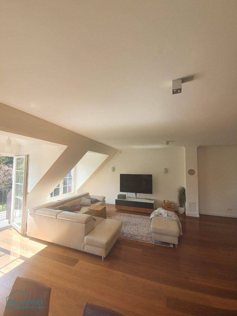 Lichtdurchflutetes Wohnzimmer mit Holzboden, gemütlicher Sitzecke und Zugang zu einem Balkon.