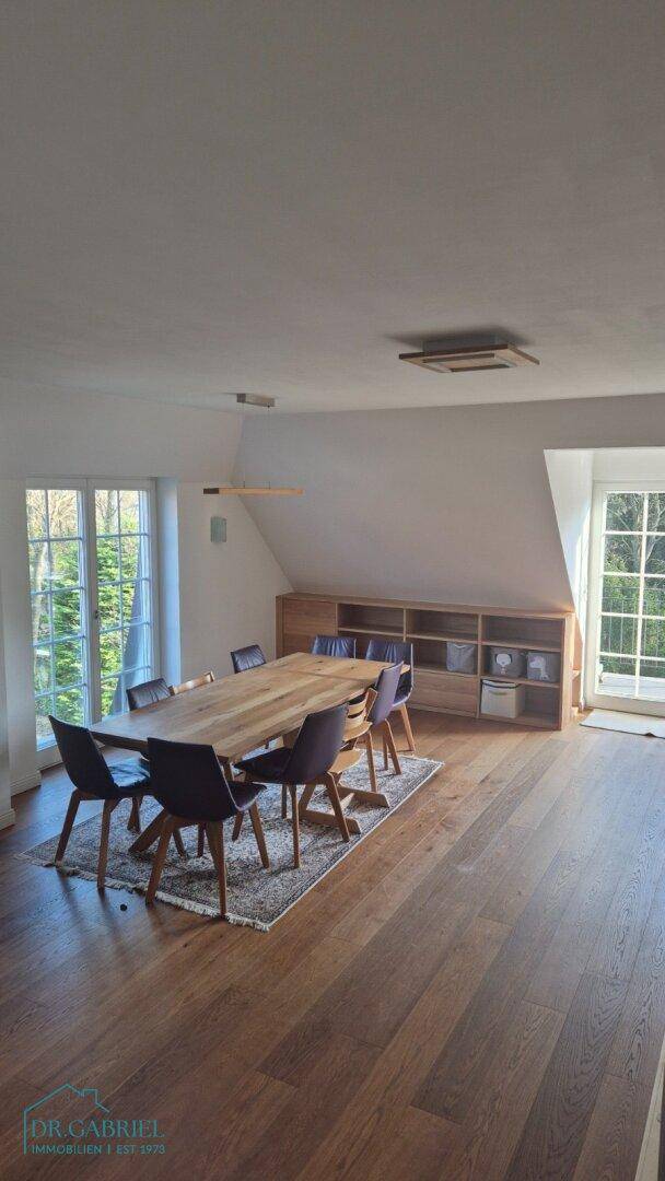 Heller Essbereich mit großem Holztisch, modernen Stühlen und Holzboden unter Dachschrägen.