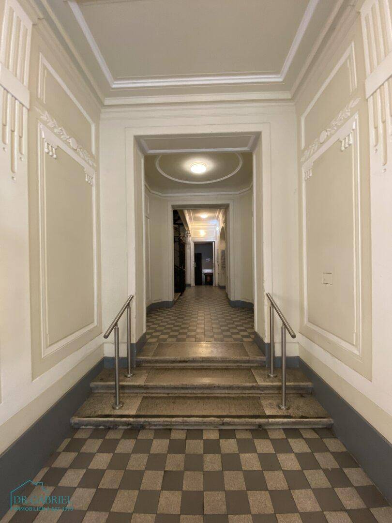 Repräsentativer Eingangsbereich mit hohen Decken, Stuckelementen und Fliesenboden.