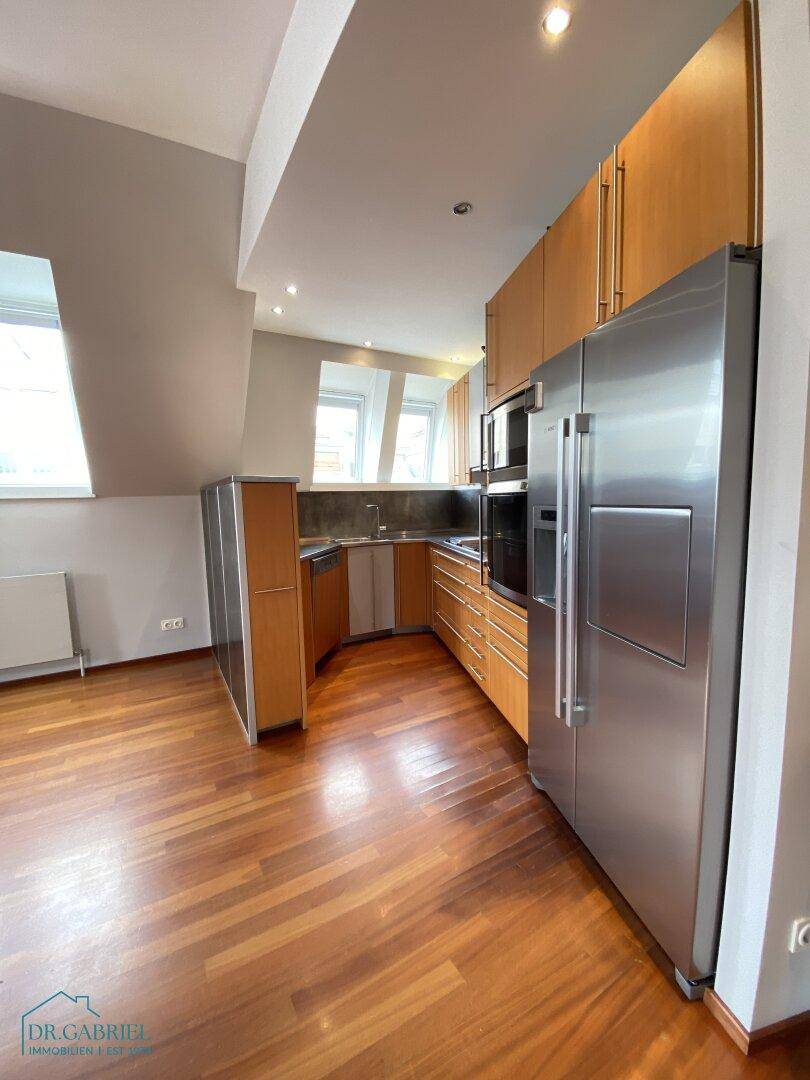 Moderne Einbauküche mit Holzfronten, Edelstahlgeräten und viel Stauraum.