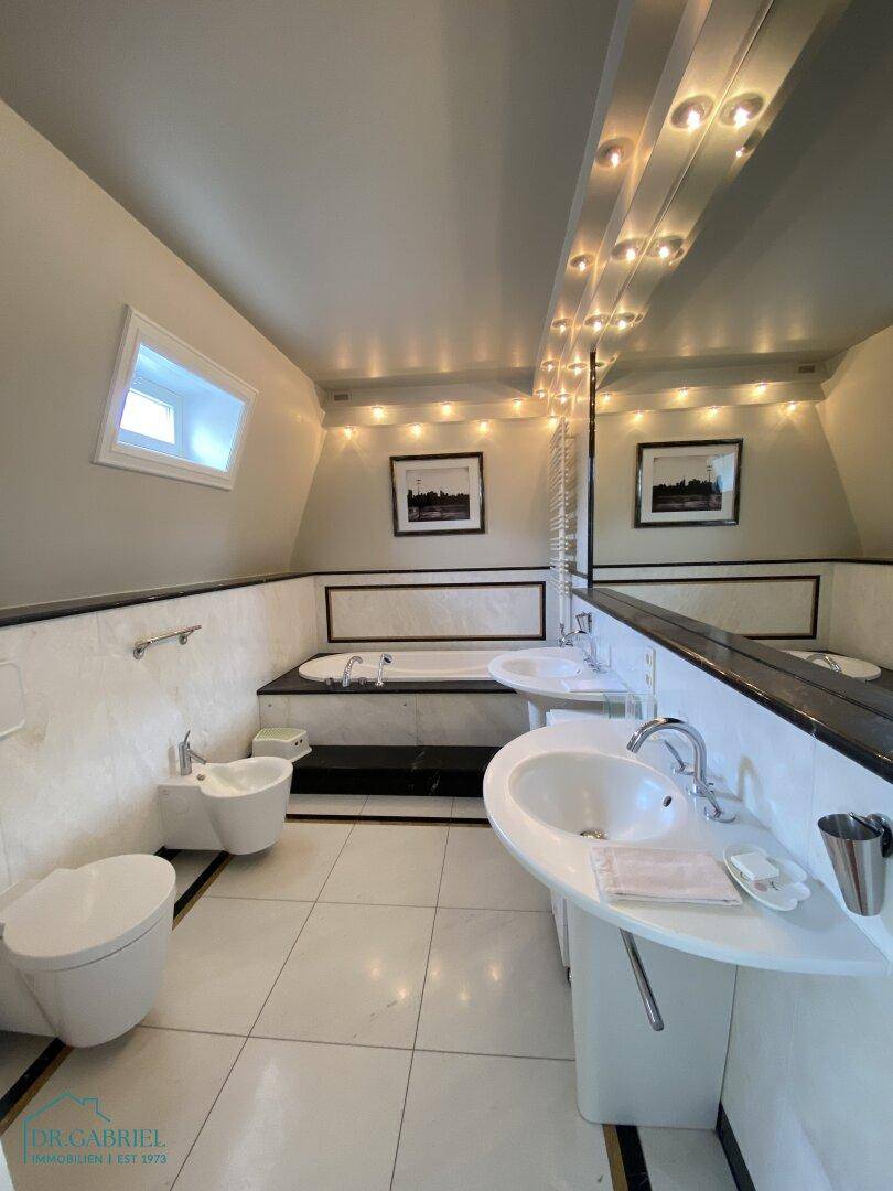 Elegantes Badezimmer mit Badewanne, Doppelwaschbecken und Bidet in modernem Design.
