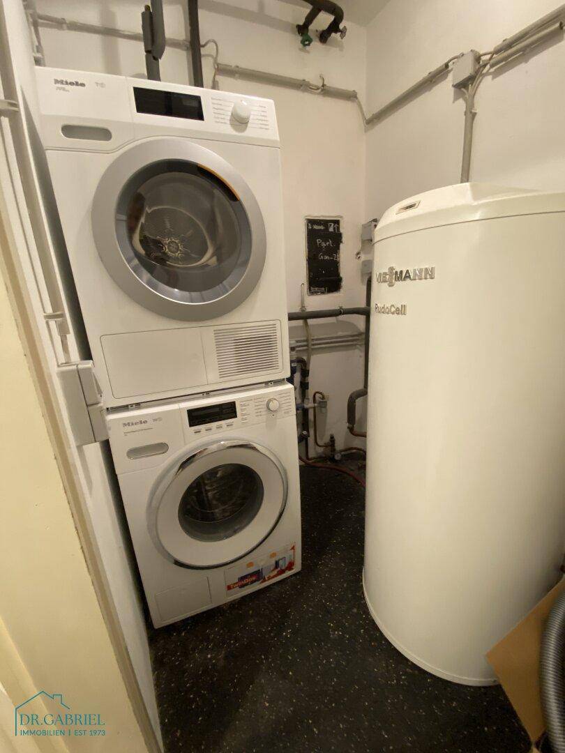 Funktionaler Hauswirtschaftsraum mit Waschmaschine, Trockner und Warmwasserspeicher.