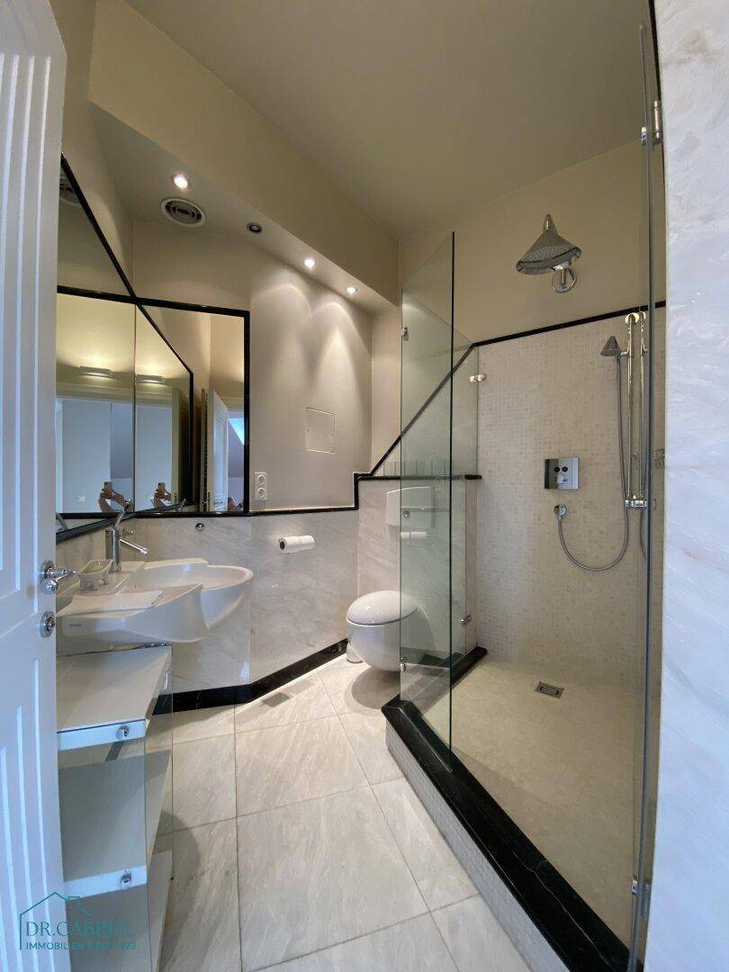 Modernes Badezimmer mit ebenerdiger Dusche, Waschtisch und eleganten Fliesen.